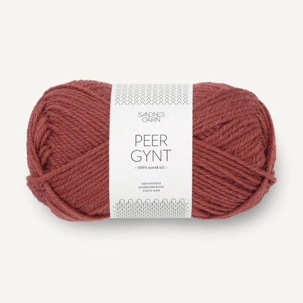 Ball of burnt orange yarn with a label on a white background