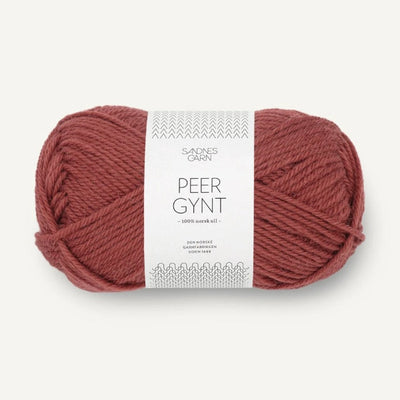 Ball of burnt orange yarn with a label on a white background
