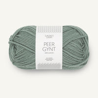 Ball of sage green yarn with a label on a white background