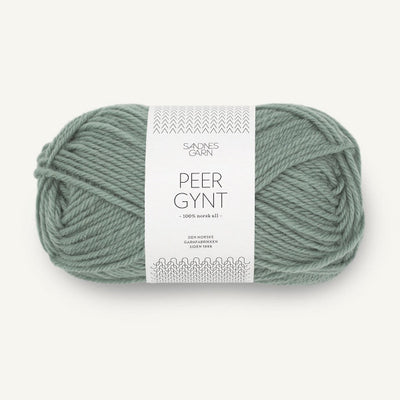 Ball of sage green yarn with a label on a white background