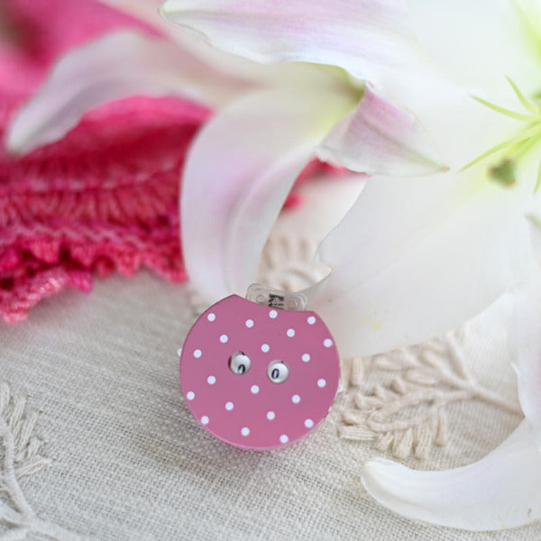 Pink polka dot row counter on a white fabric background