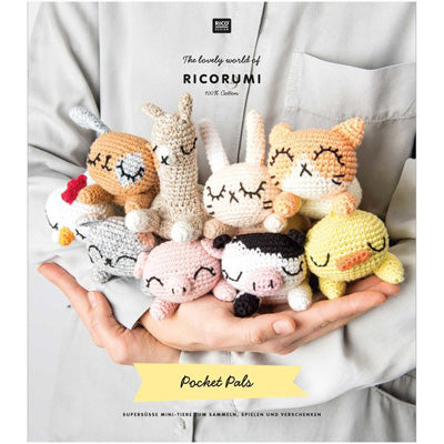 Hand holding a collection of small, crocheted animal toys with 'Ricorumi' branding.