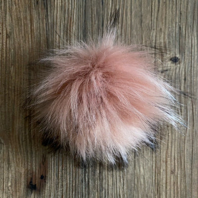 Pink fluffy pom-pom on a wooden surface