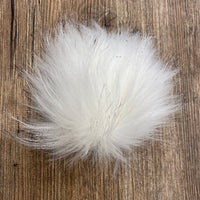 White fluffy pom-pom on a wooden surface