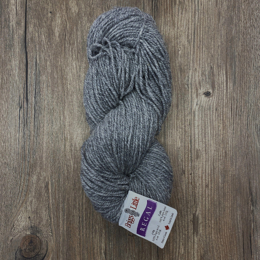Gray skein of yarn with a label on a wooden surface