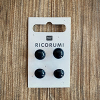 A package of 4 black plastic eyes on a wood background