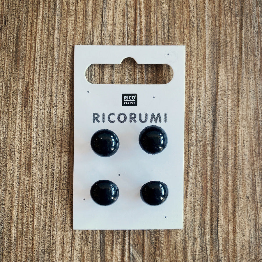 A package of 4 black plastic eyes on a wood background