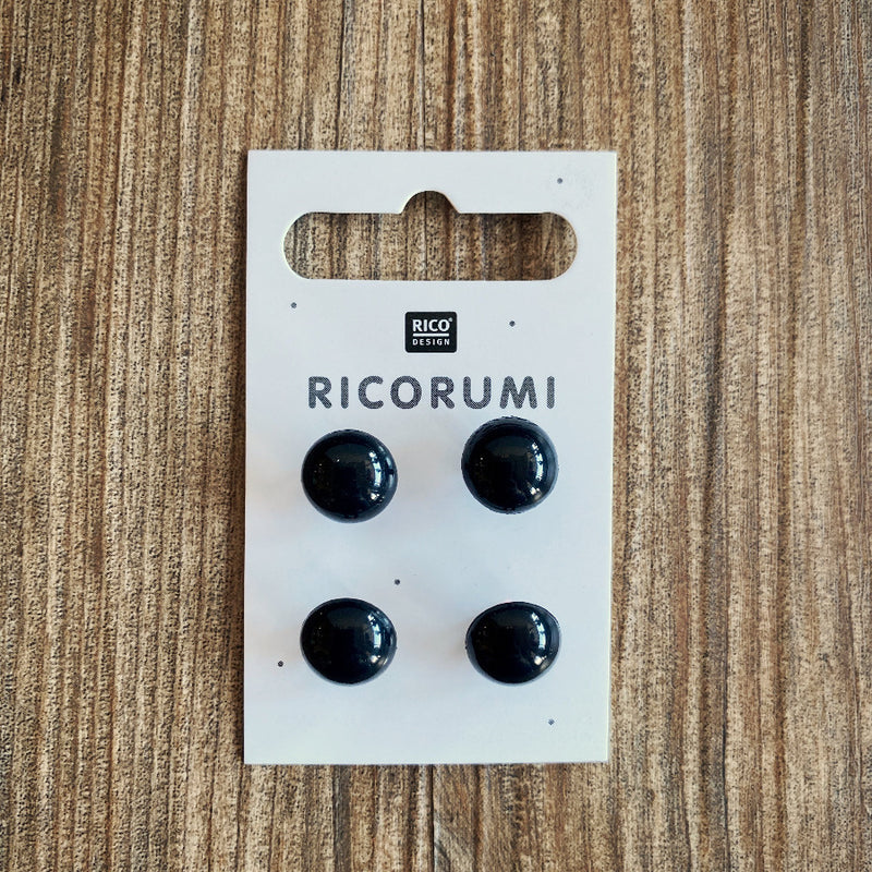 A package of 4 black plastic eyes on a wood background