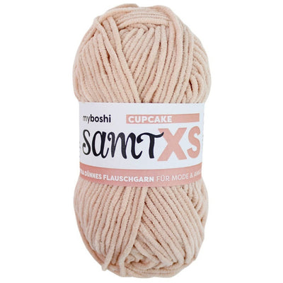 Pale pink chenille yarn ball with a label on a white background