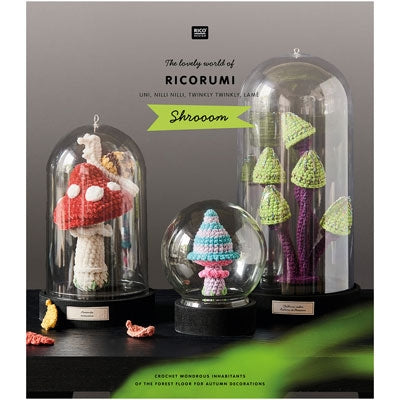 Crocheted mushroom decorations under glass domes with 'Ricorumi' branding.