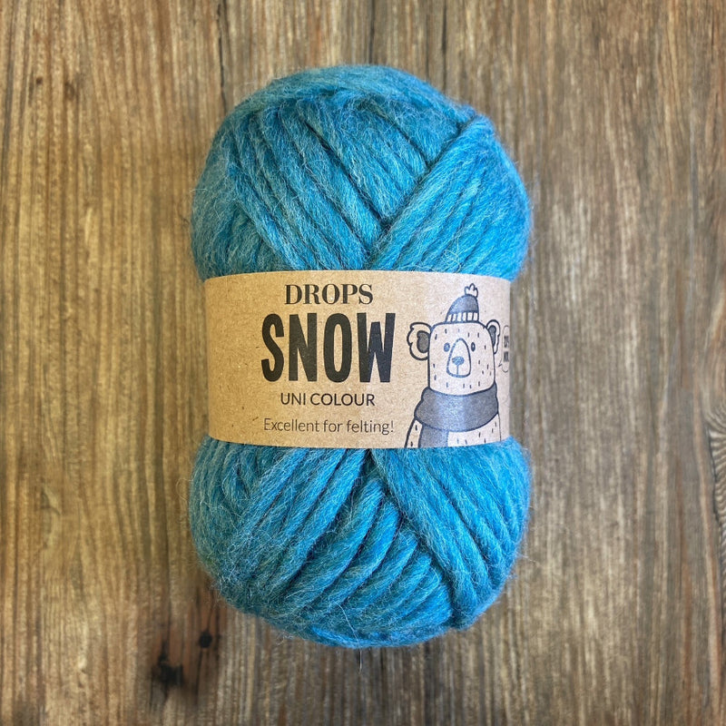 Blue skein of yarn with a "Drops Snow" label on a wooden surface