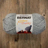 Gray skein of Bernat Softee Chunky yarn on a wooden surface