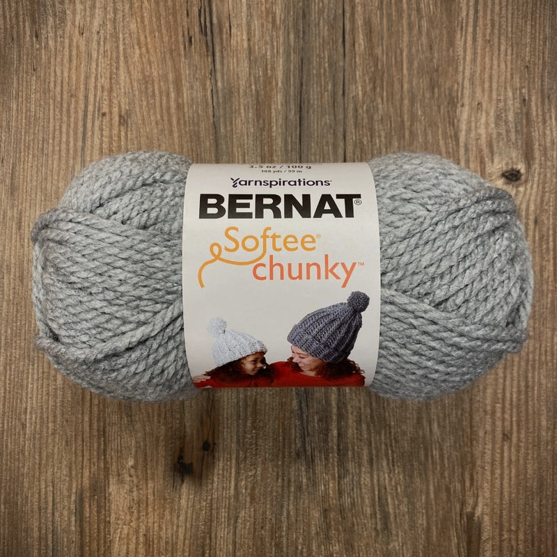 Gray skein of Bernat Softee Chunky yarn on a wooden surface