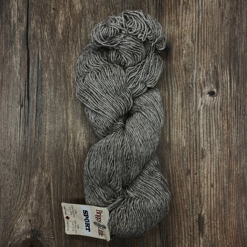 Gray skein of yarn with a label on a wooden surface