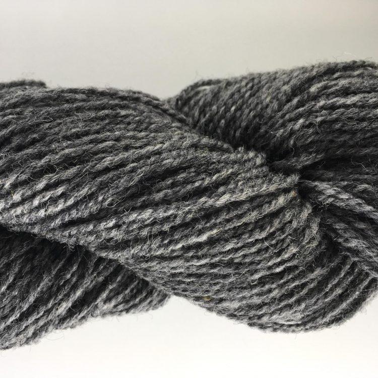 Close-up of a skein of dark gray yarn on a white background