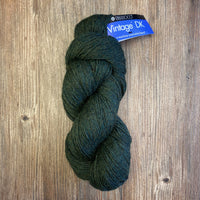 Dark green skein of yarn with a label on a wooden surface