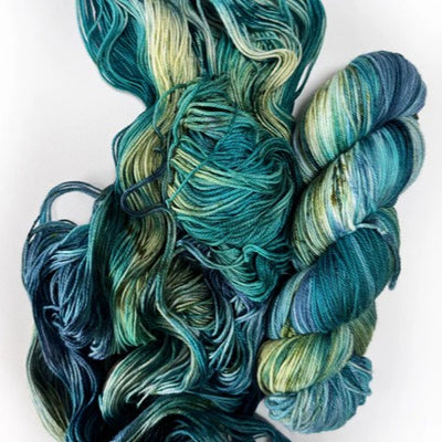Skeins and loose multicoloured yarn in blues and greens on a white background