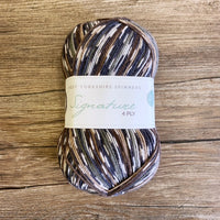 Multicolored yarn skein with a label on a wooden surface